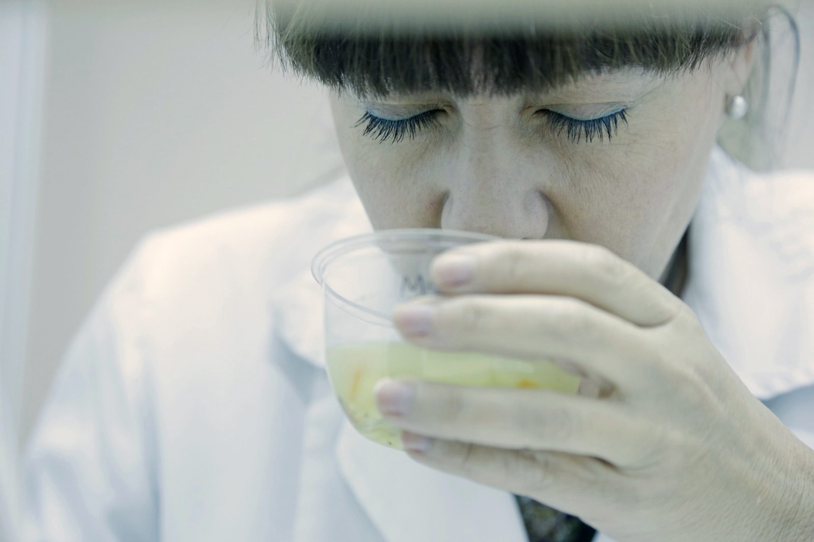 A trained panel assessor smelling a coded sample during a tasting session